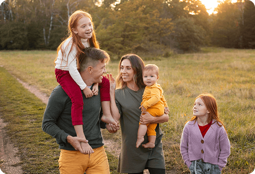 Family walking in a field at sunset